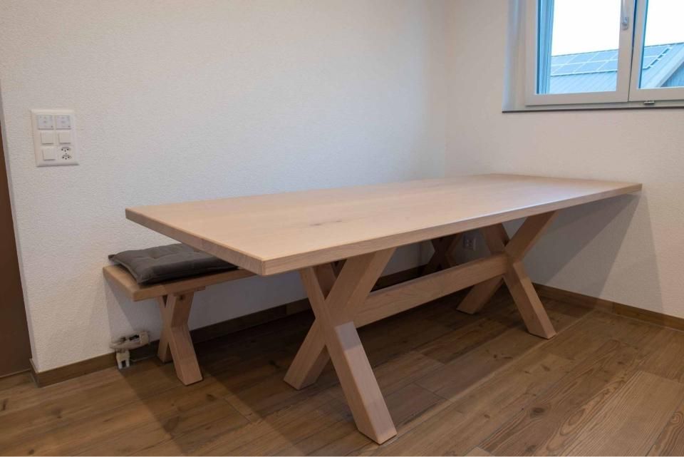 Ein Holztisch und eine Bank in einem Raum mit einem Fenster.