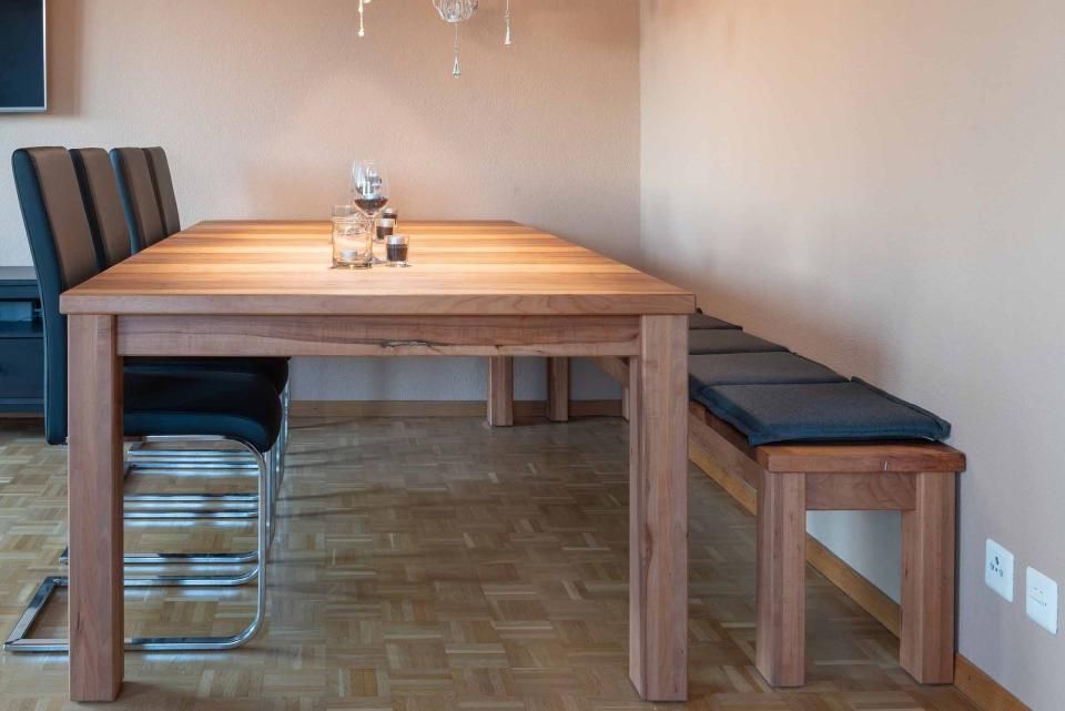Ein Holztisch mit Stühlen und einer Bank in einem Esszimmer.