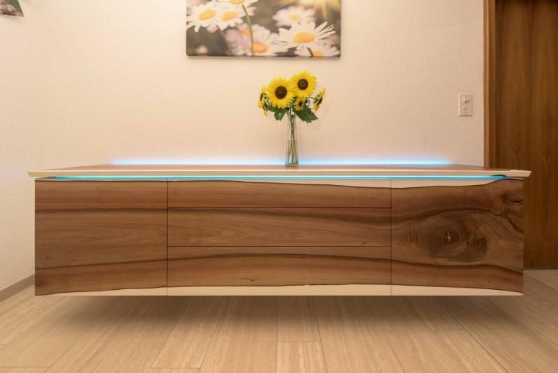 Eine hölzerne Kommode mit einer Vase mit Sonnenblumen darauf.