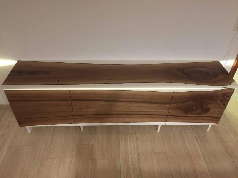 Eine Holzkommode steht auf einem Holzboden neben einer Wand.