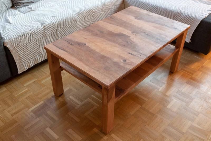 Ein Couchtisch aus Holz steht in einem Wohnzimmer neben einer Couch auf einem Holzboden.