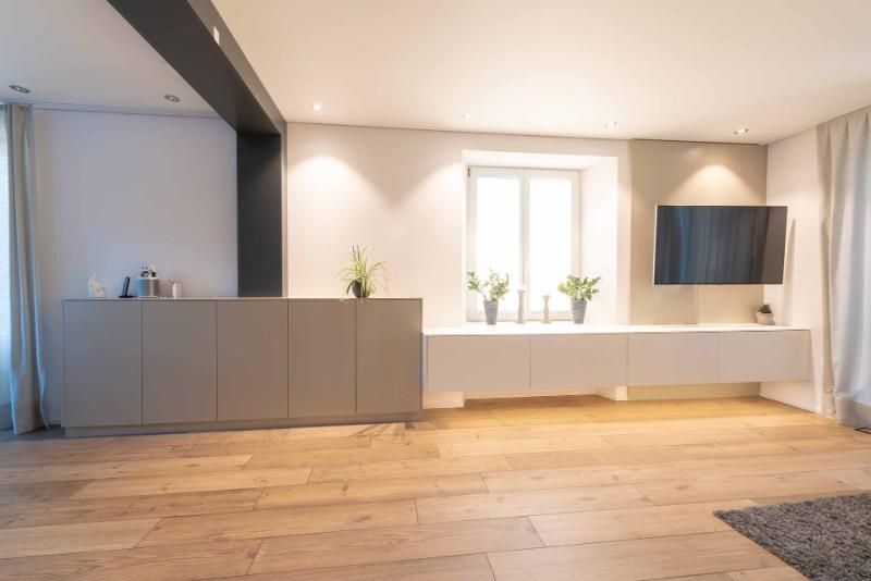 Ein Wohnzimmer mit Hartholzböden und einem Flachbildfernseher an der Wand.