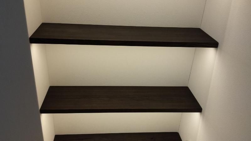 Ein Schrank mit drei Regalen und einer Lampe auf dem untersten Regal.