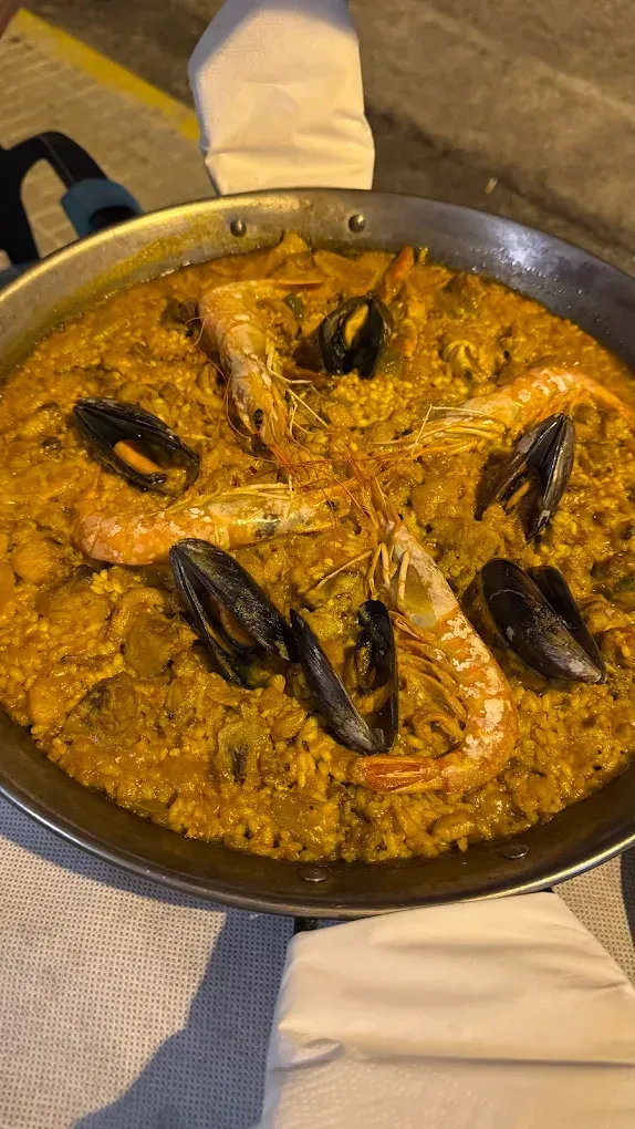 Sartén de guiso cremoso de mariscos a la naranja con mejillones por encima sobre una mesa