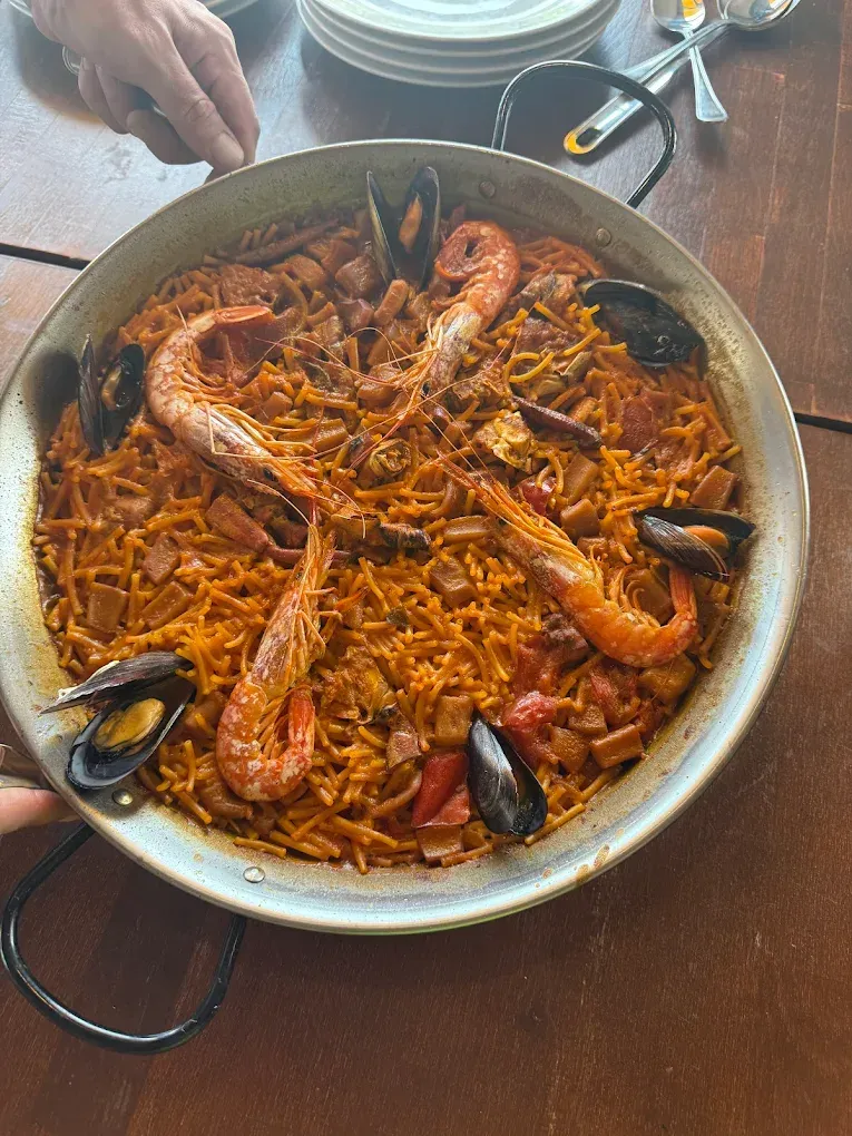 Paella de marisco en una sartén grande con gambas, mejillones y arroz con azafrán sobre una mesa.