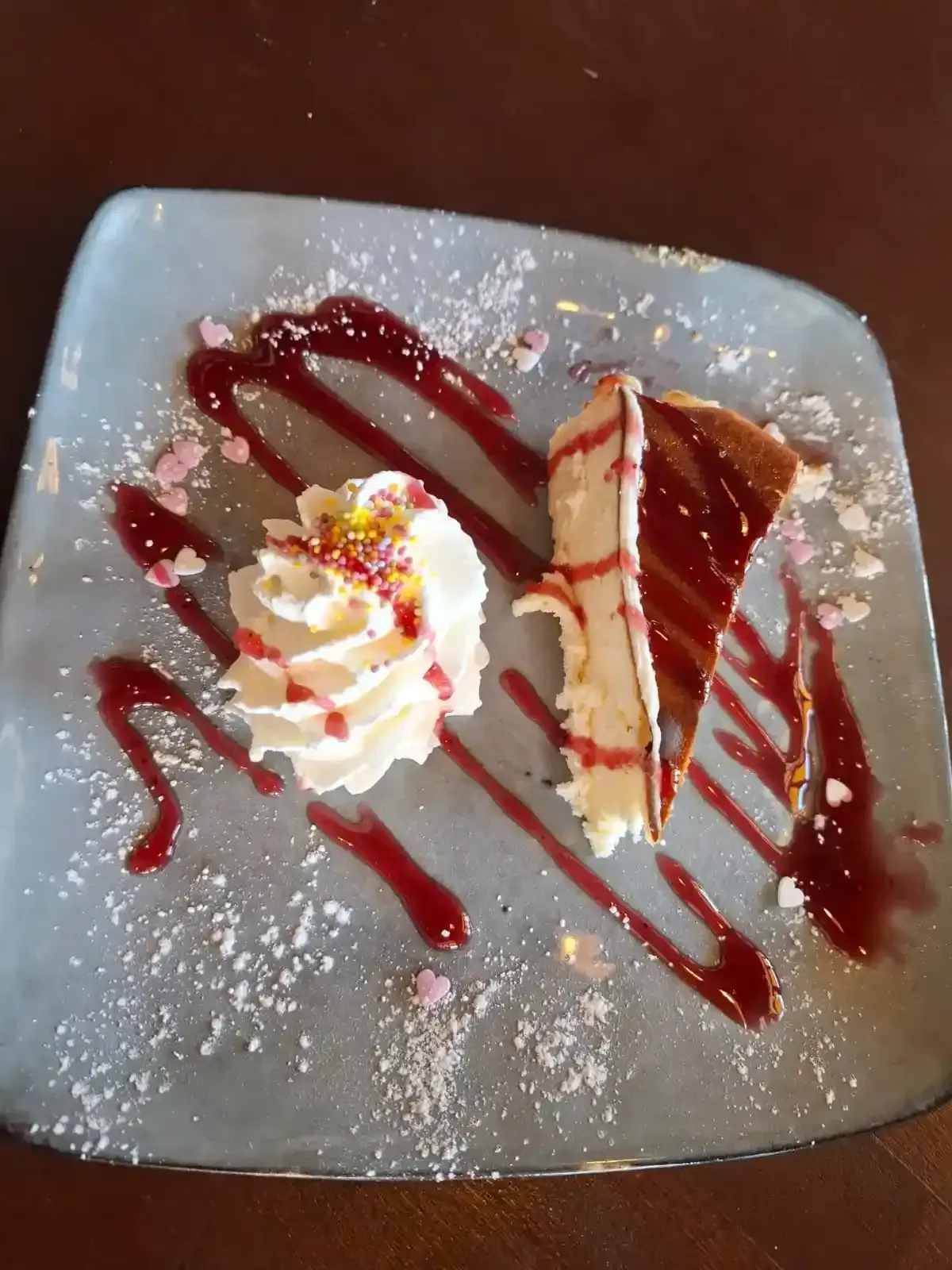 Plato de postre con crema batida, sirope de chocolate y azúcar glas sobre un plato cuadrado.