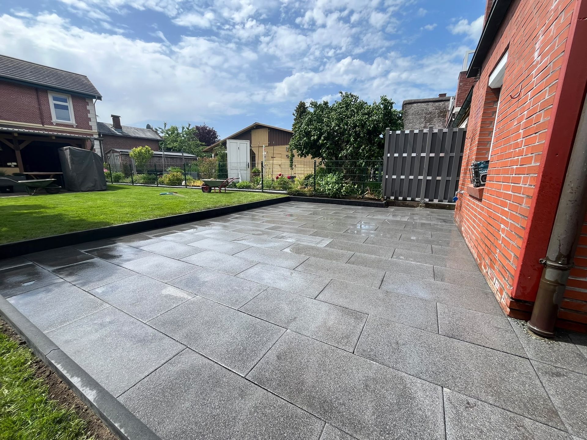 Gepflasterte Terrasse mit gepflegtem Garten von Gartenpflege Persson