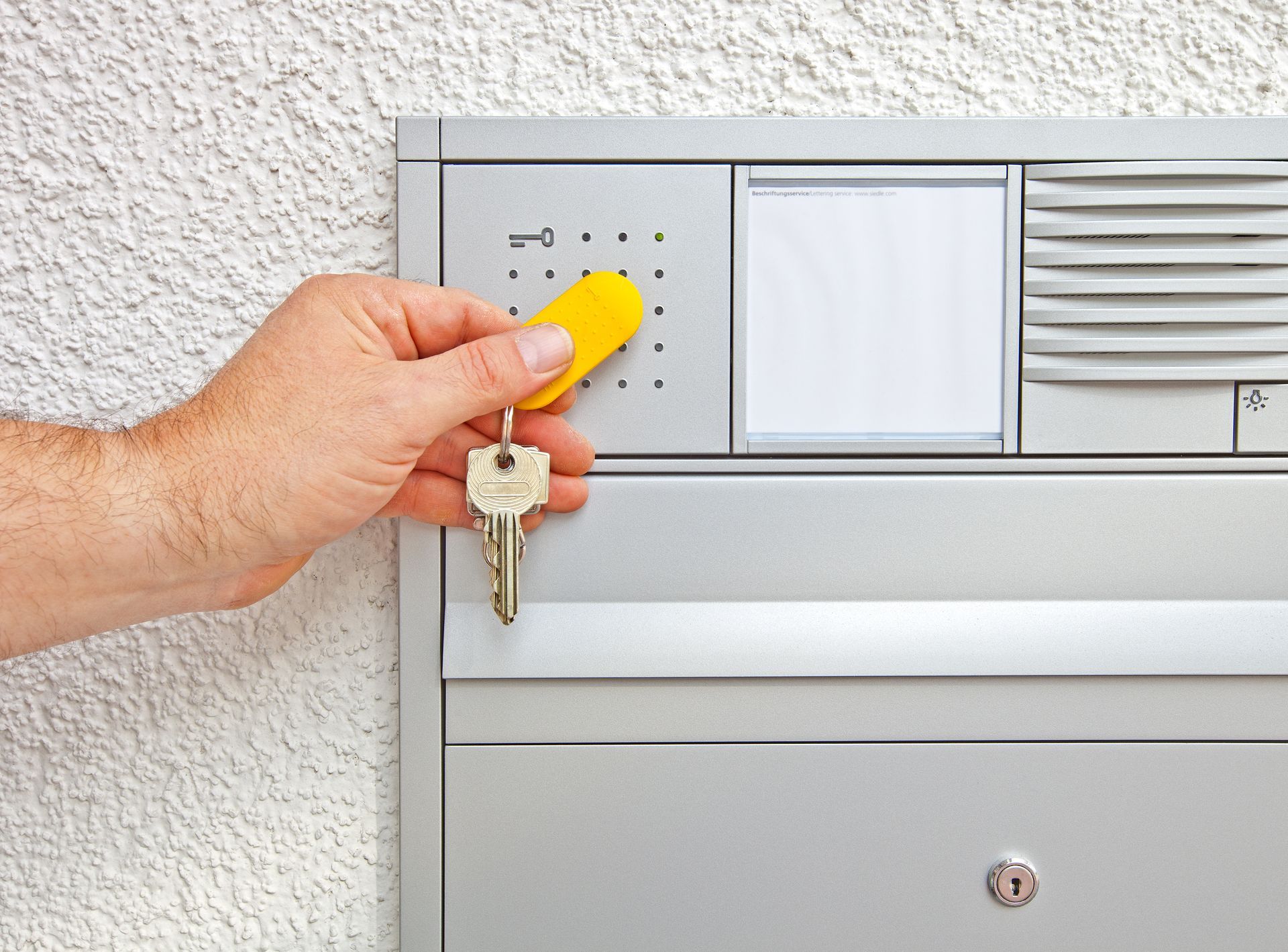 Une main passant un badge d'immeuble sur un accès