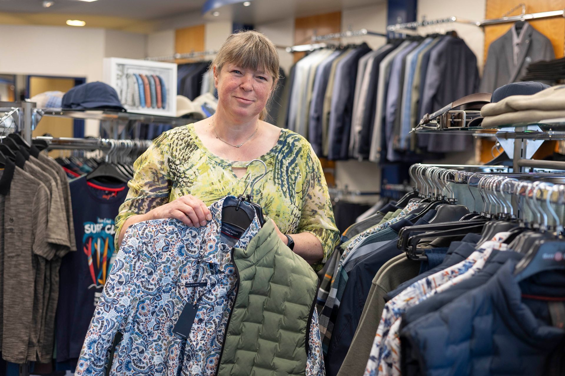 Eine Frau hält in einem Bekleidungsgeschäft eine Jacke in der Hand.
