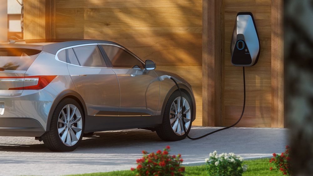 An einer Ladestation vor einem Haus wird ein Elektroauto aufgeladen.