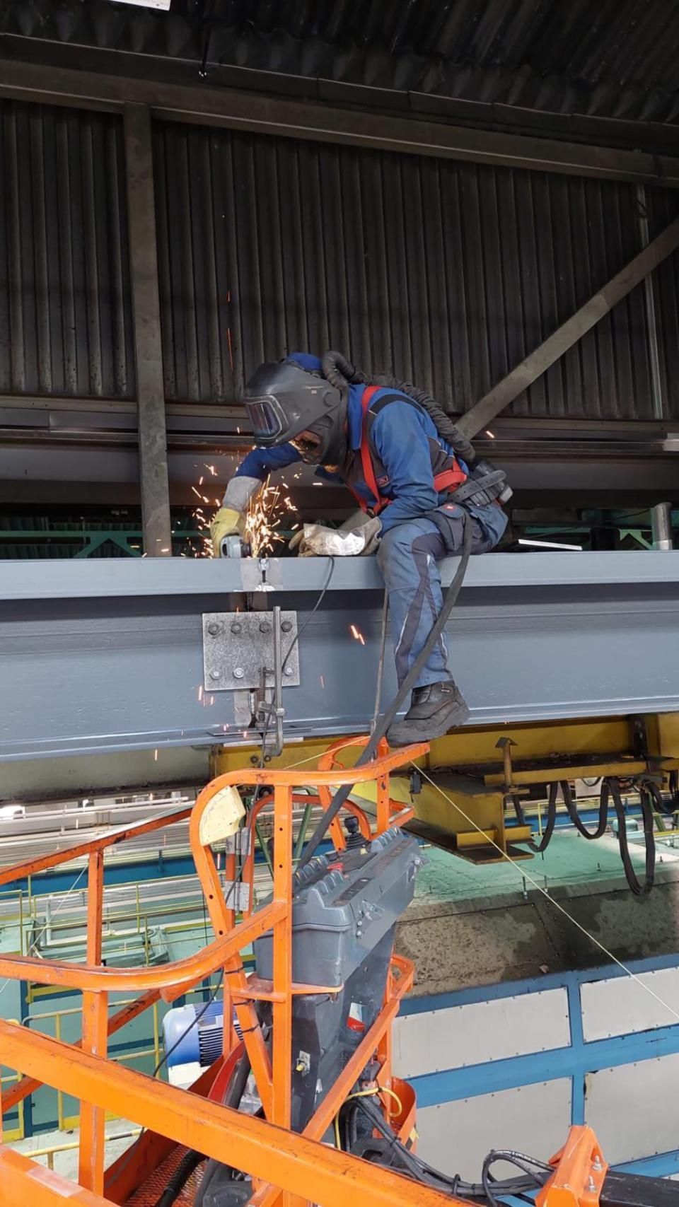 Un homme soude une structure métallique dans une usine.