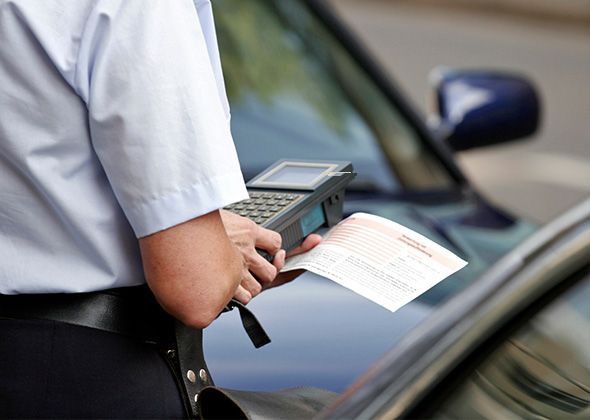 Un agent remplit une contravention devant une voiture
