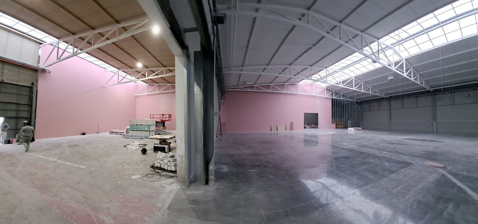 Un gran almacén vacío con una pared rosa y un suelo brillante.