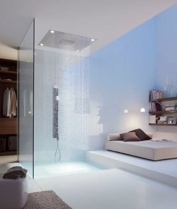 Chambre moderne avec douche à effet pluie en verre et lit surélevé sur sol blanc
