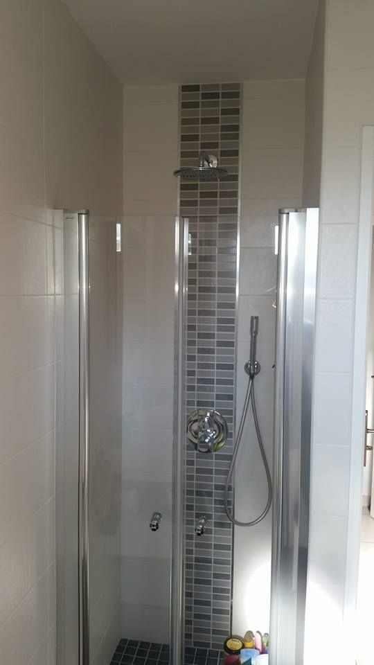 Douche moderne avec frise carrelée, robinetterie chromée et murs blancs.