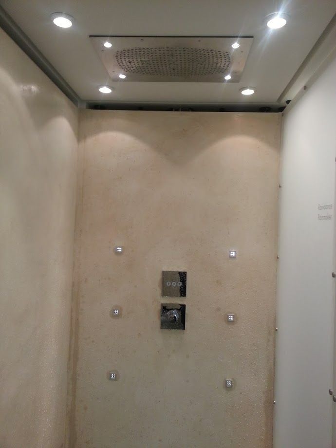 Pièce beige vide avec plafonnier, une bouche d'aération et des prises murales au centre.