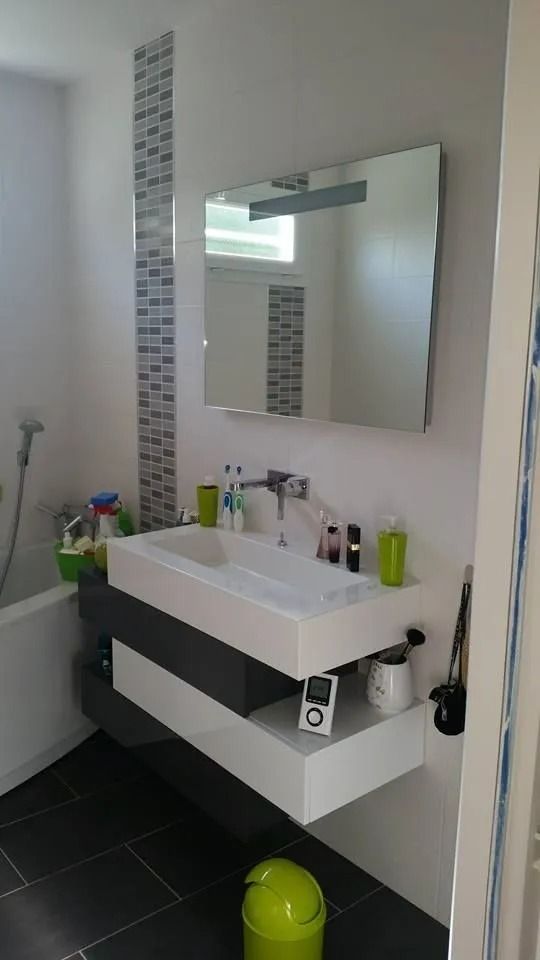 Salle de bain moderne avec lavabo mural, miroir, carrelage noir au sol et poubelle verte