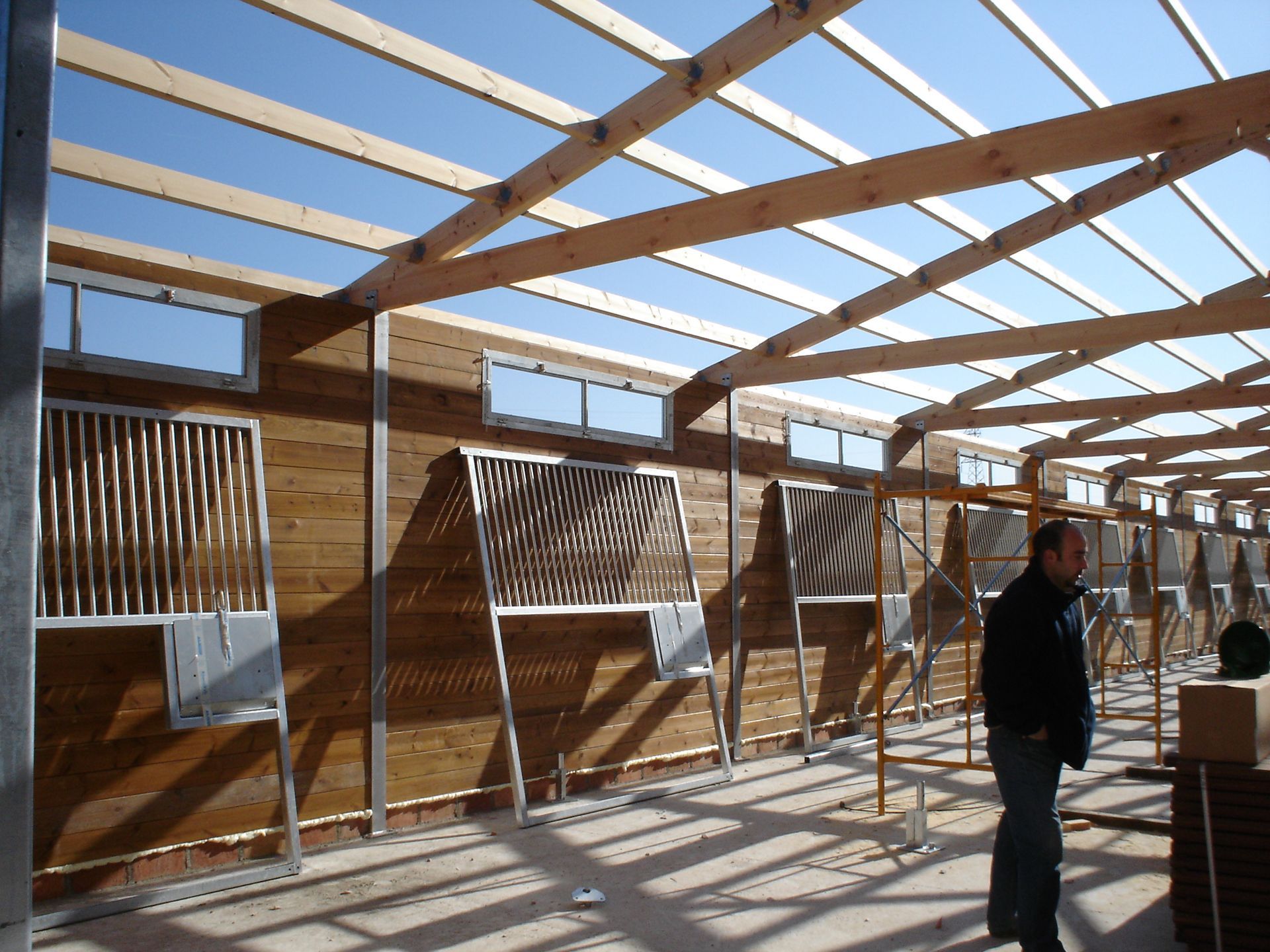 Interior de un edificio de madera parcialmente construido con una persona de pie dentro.
