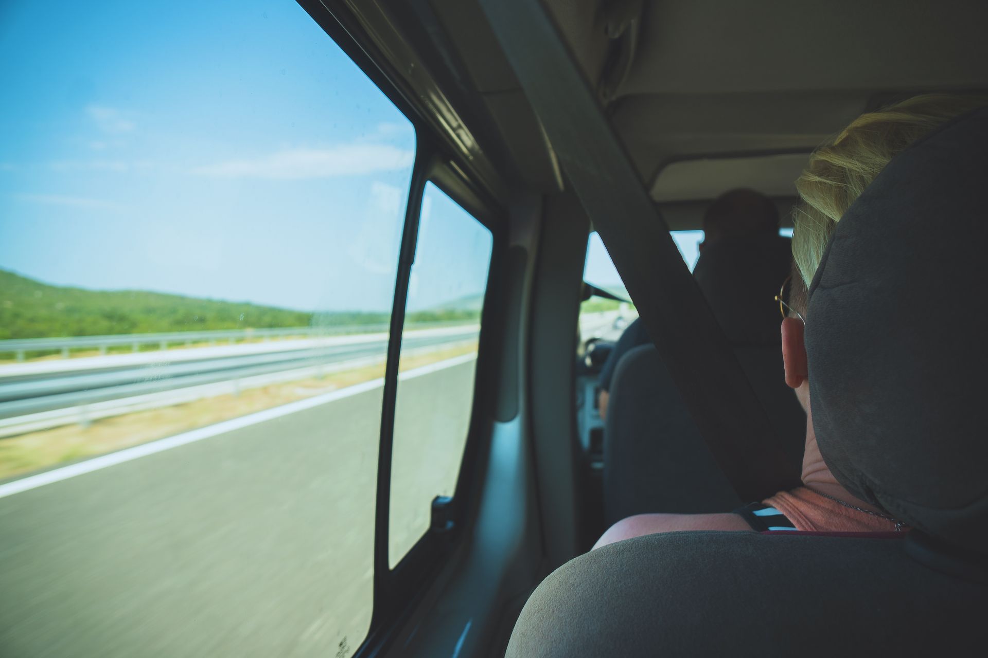 Vue d'une personne de dos dans un minibus côté fenêtre et le conducteur en arrière plan