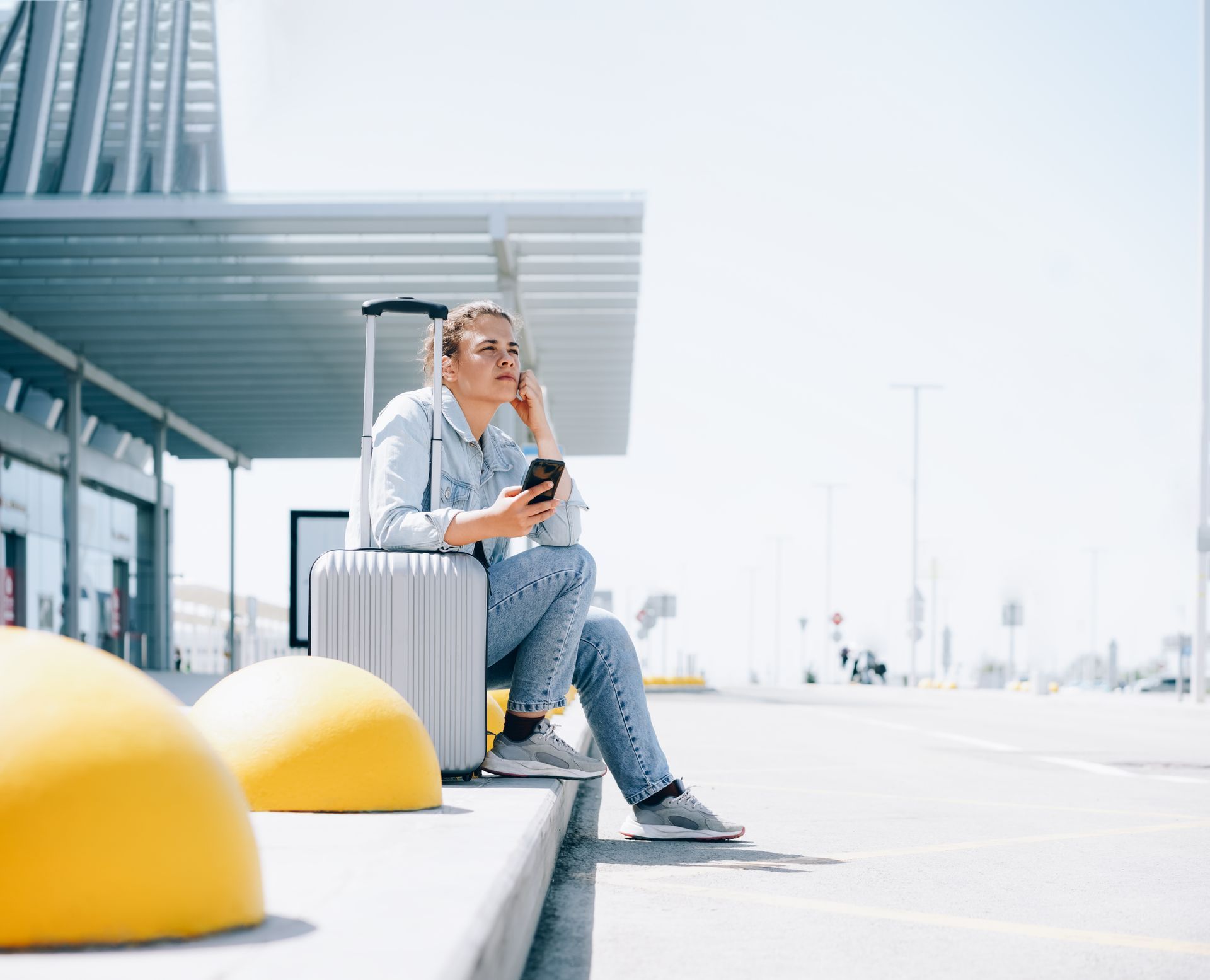 Une femme avec une valise au téléphone devant un aéroport