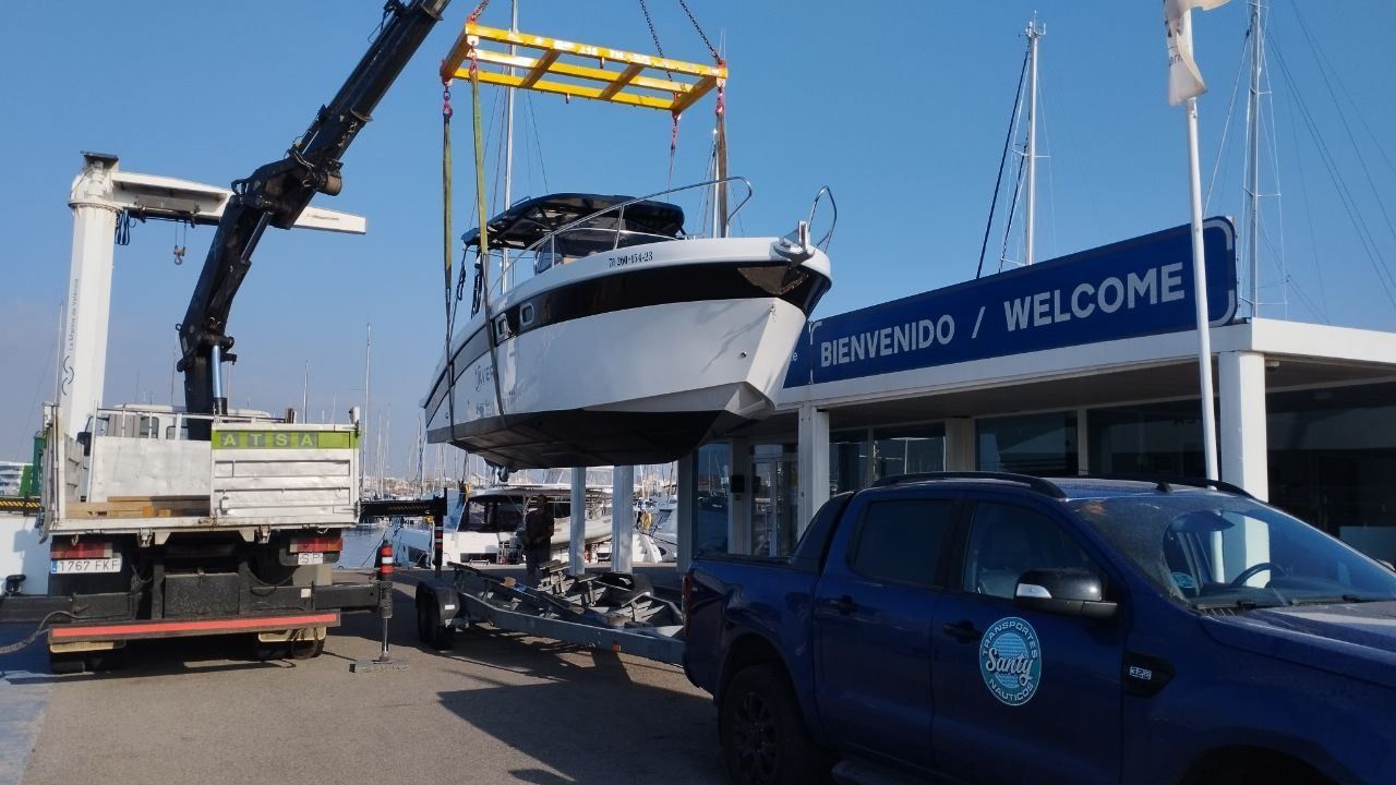 Una grúa levanta un barco al agua.