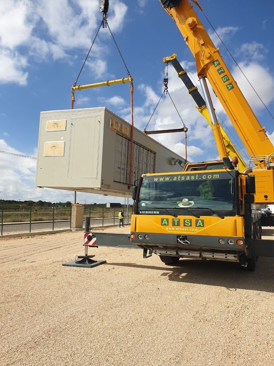 Una gran grúa amarilla está levantando un contenedor grande