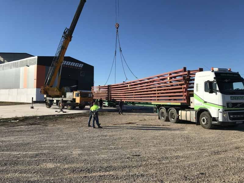 Un camión está siendo levantado por una grúa en un estacionamiento.