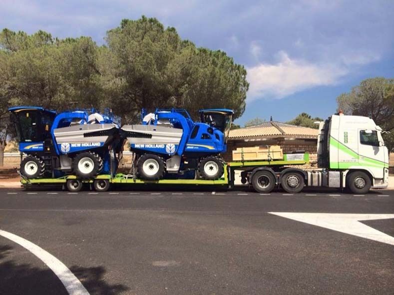 Un camión transporta dos tractores en un remolque.