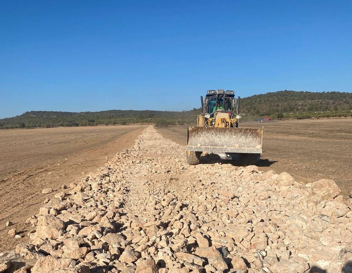 Una excavadora está moviendo rocas en un camino de tierra