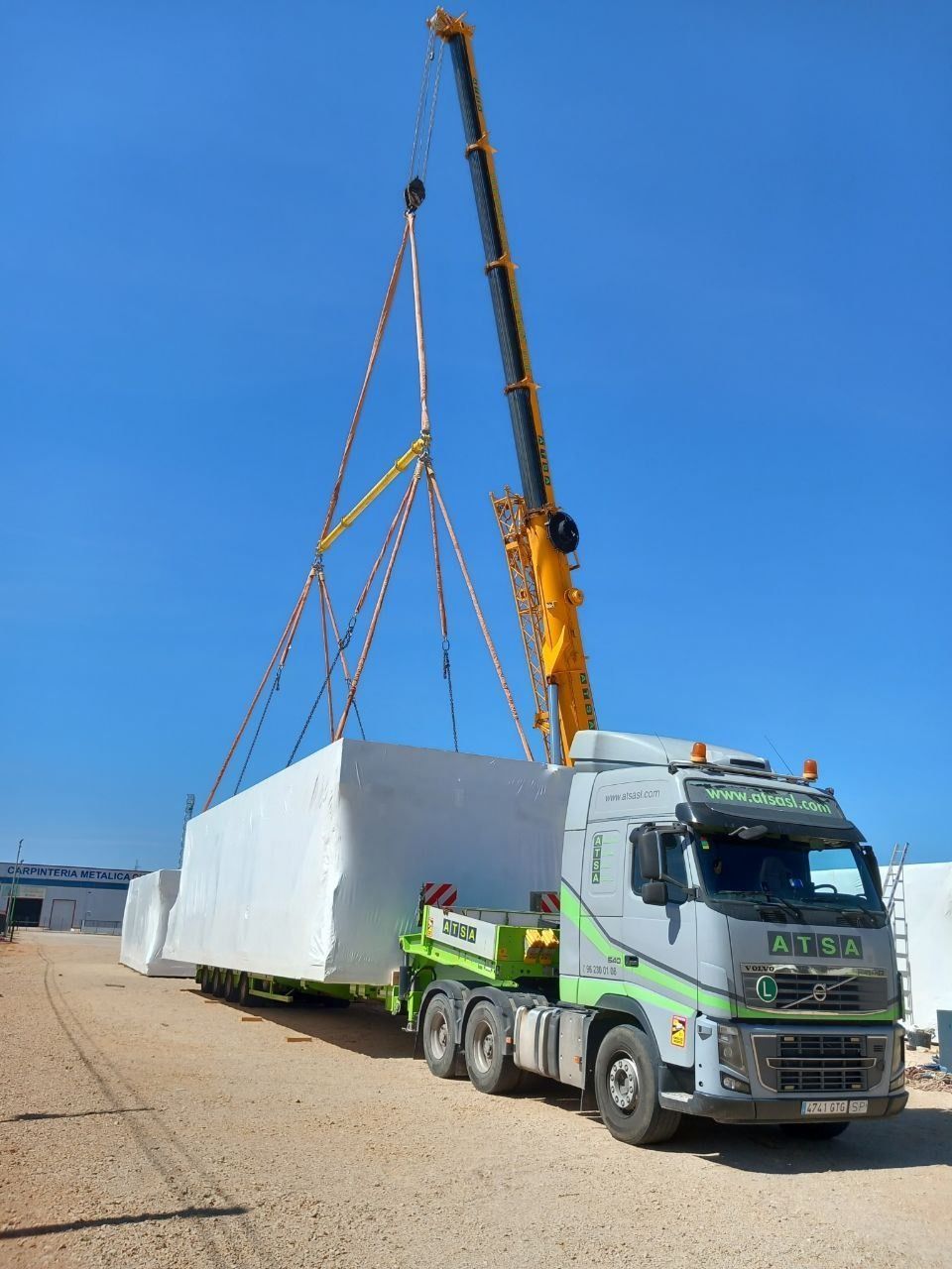 Un camión está siendo levantado por una grúa en un lote de grava.