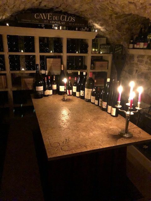 Grande table en bois avec chandelles allumées et bouteilles de vins dans une cave