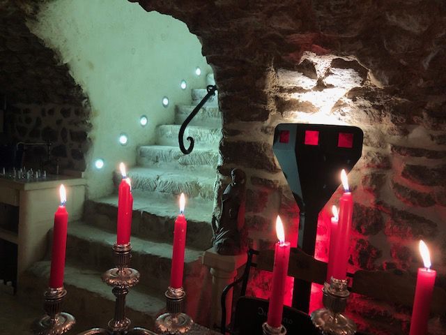 Murs en pierre de la cave et chandelles rouges menant à un escalier