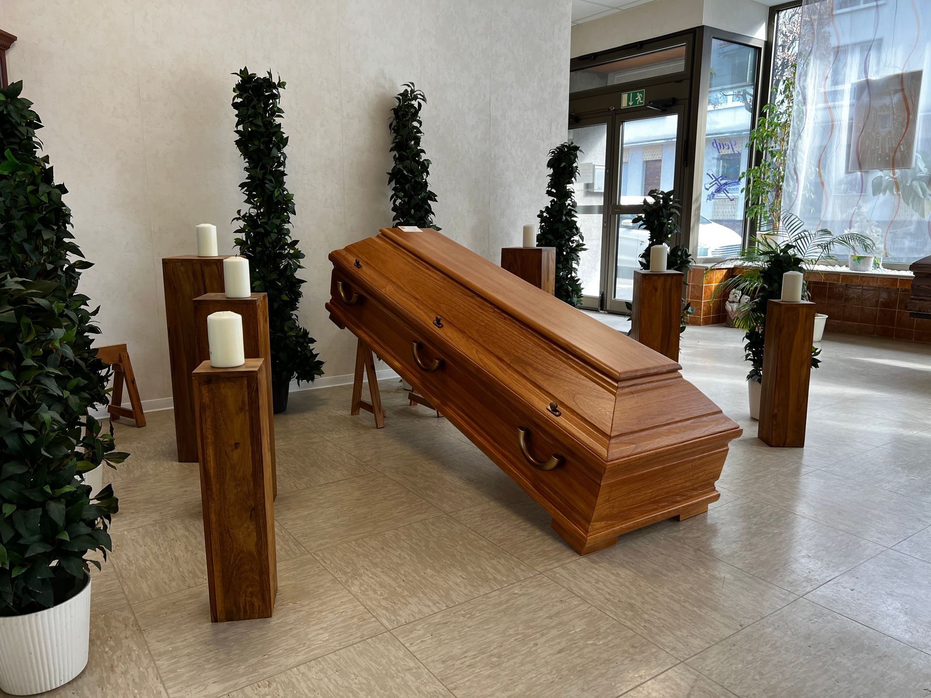Ein Holzsarg in einem Raum mit Kerzen und Bäumen. Foto von den Bestattungen Jeup
