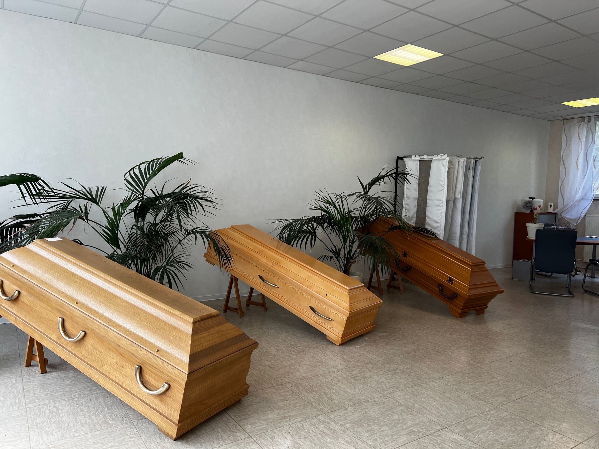 Drei Holzsärge stehen in einem Raum mit Pflanzen. Foto von den Bestattungen Jeup