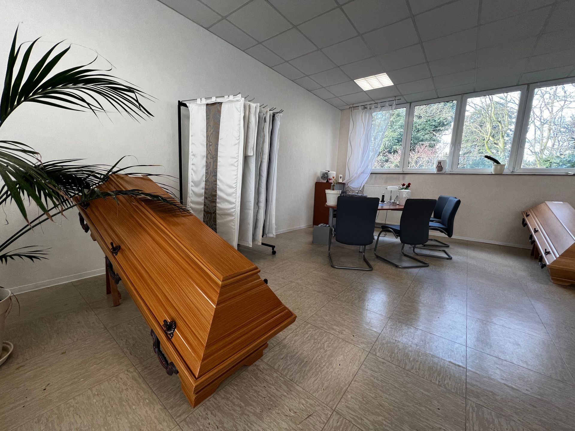 In einem Raum steht ein Holzsarg neben einem Tisch und Stühlen. Foto von den Bestattungen Jeup