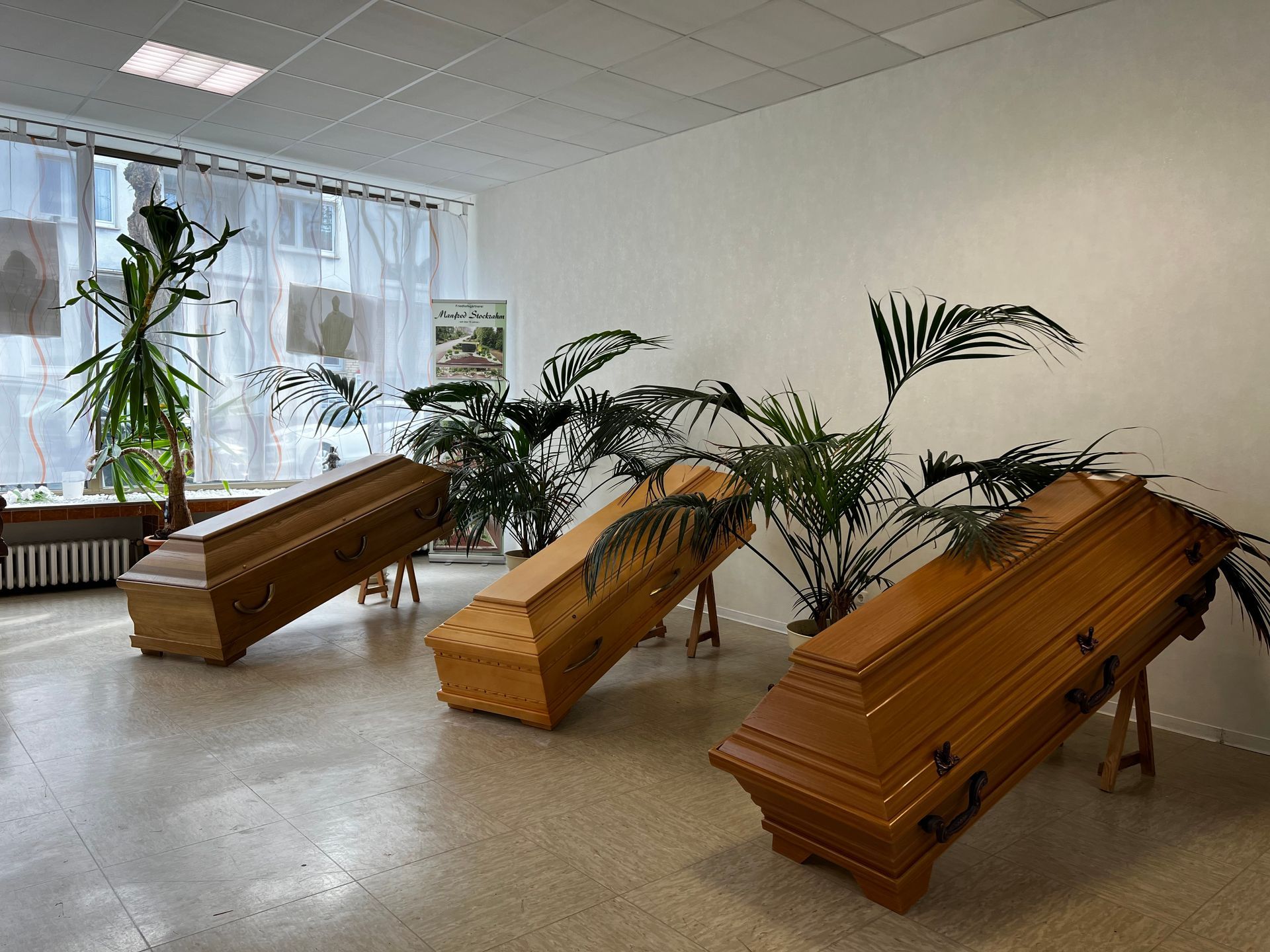 Drei Holzsärge stehen in einem Raum mit Pflanzen. Foto von den Bestattungen Jeup