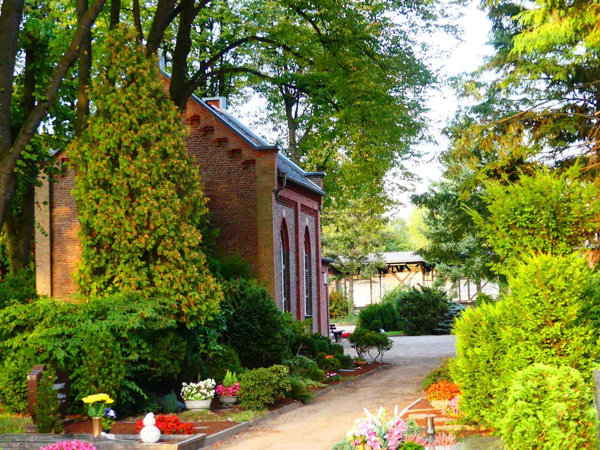 Ein Backsteingebäude ist von Bäumen und Büschen umgeben. Foto von den Bestattungen Jeup