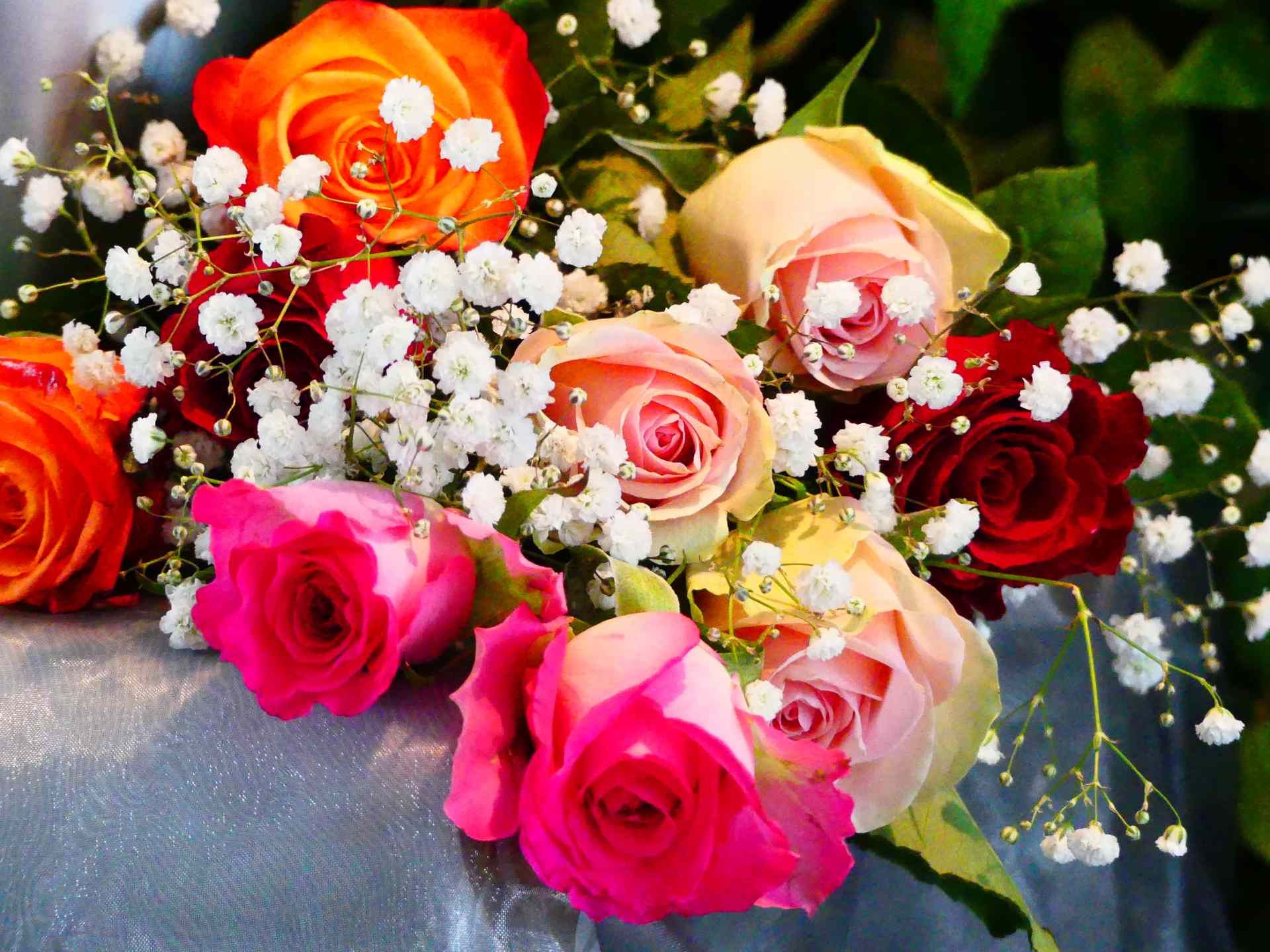 Ein Strauß verschiedenfarbiger Rosen mit Schleierkraut. Foto von den Bestattungen Jeup