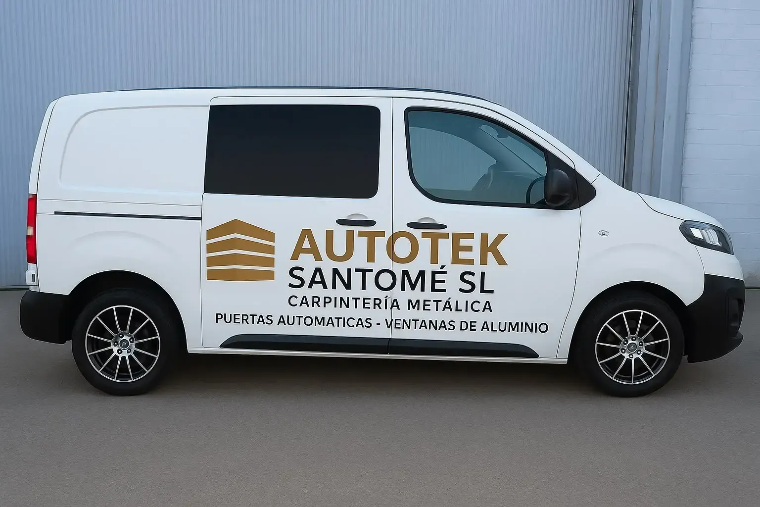 Furgoneta de carga blanca con el letrero de AUTOTEK SANTOME estacionada junto a un muro de chapa ondulada.