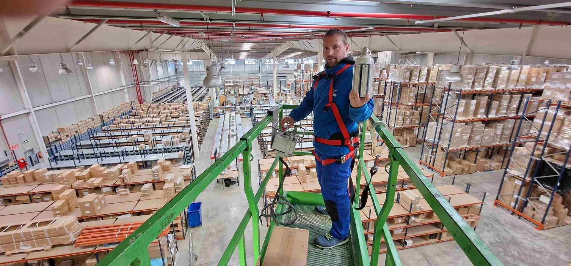 Un hombre con un mono azul y un arnés de seguridad sosteniendo un dispositivo.