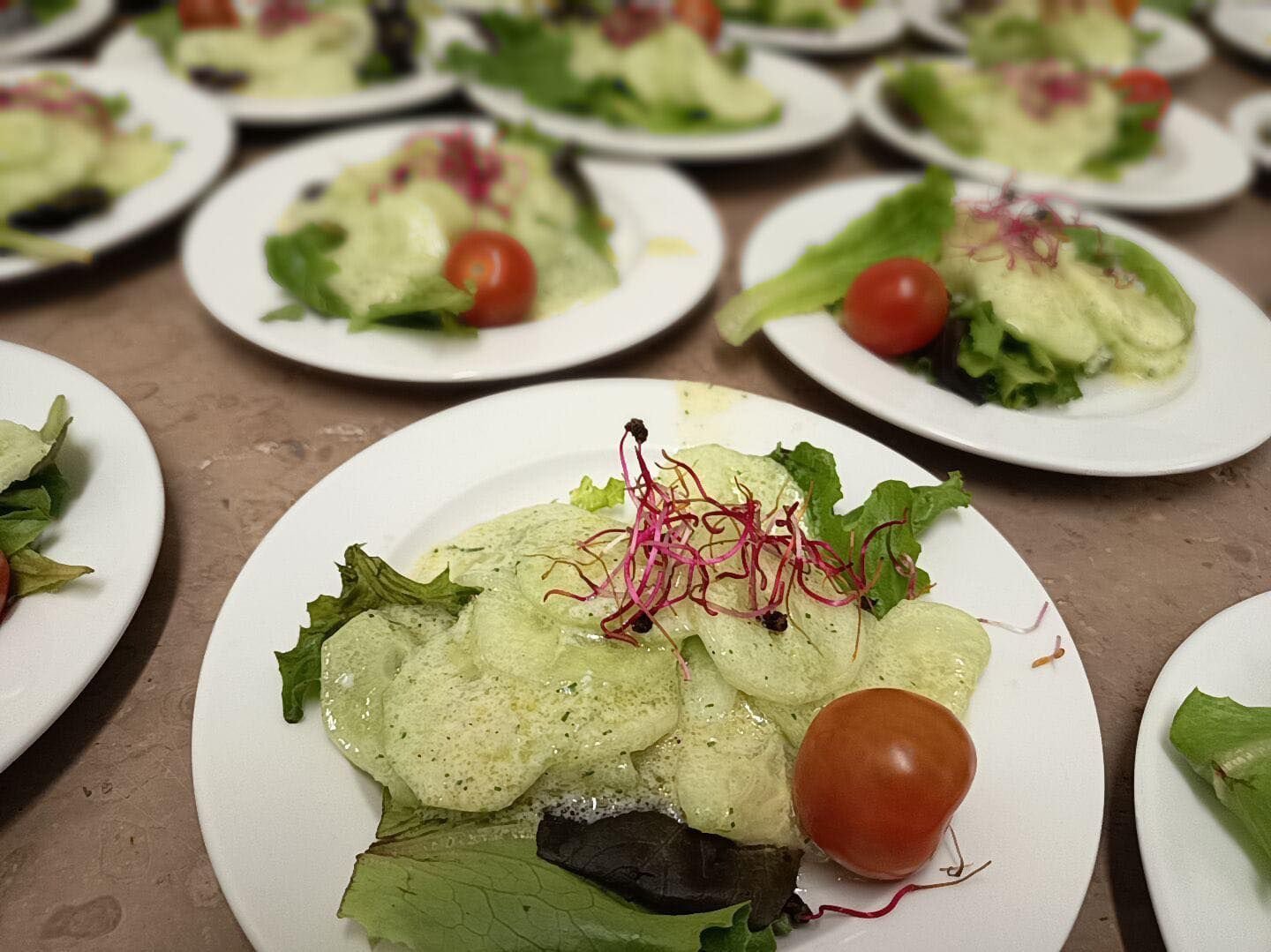 Des assiettes de salade composées de laitue, de tomates et de légumes verts disposées sur une table.