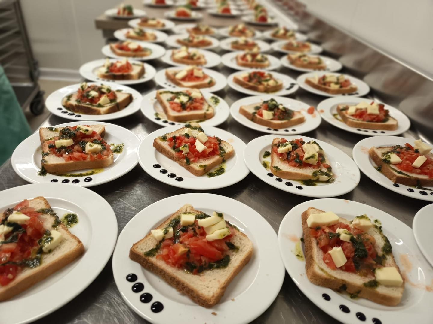 Plusieurs rangées d'assiettes de pain avec des tomates et du fromage.