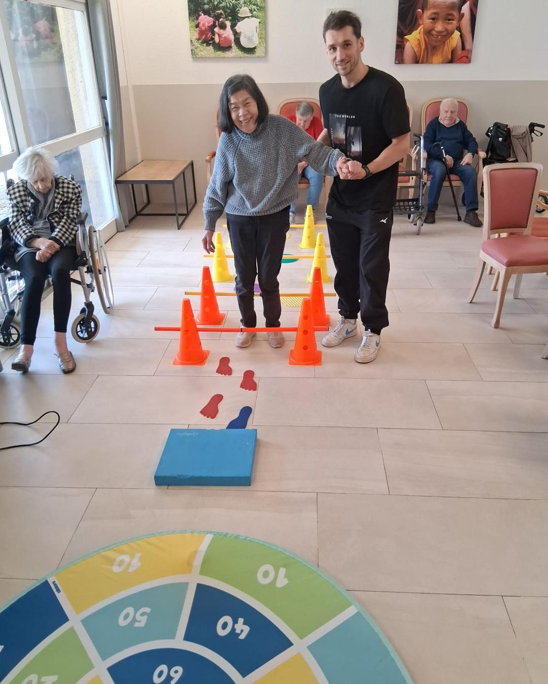 Des personnes sur un parcours d'obstacles composé de cônes dans une pièce, avec un tapis numéroté devant elles.