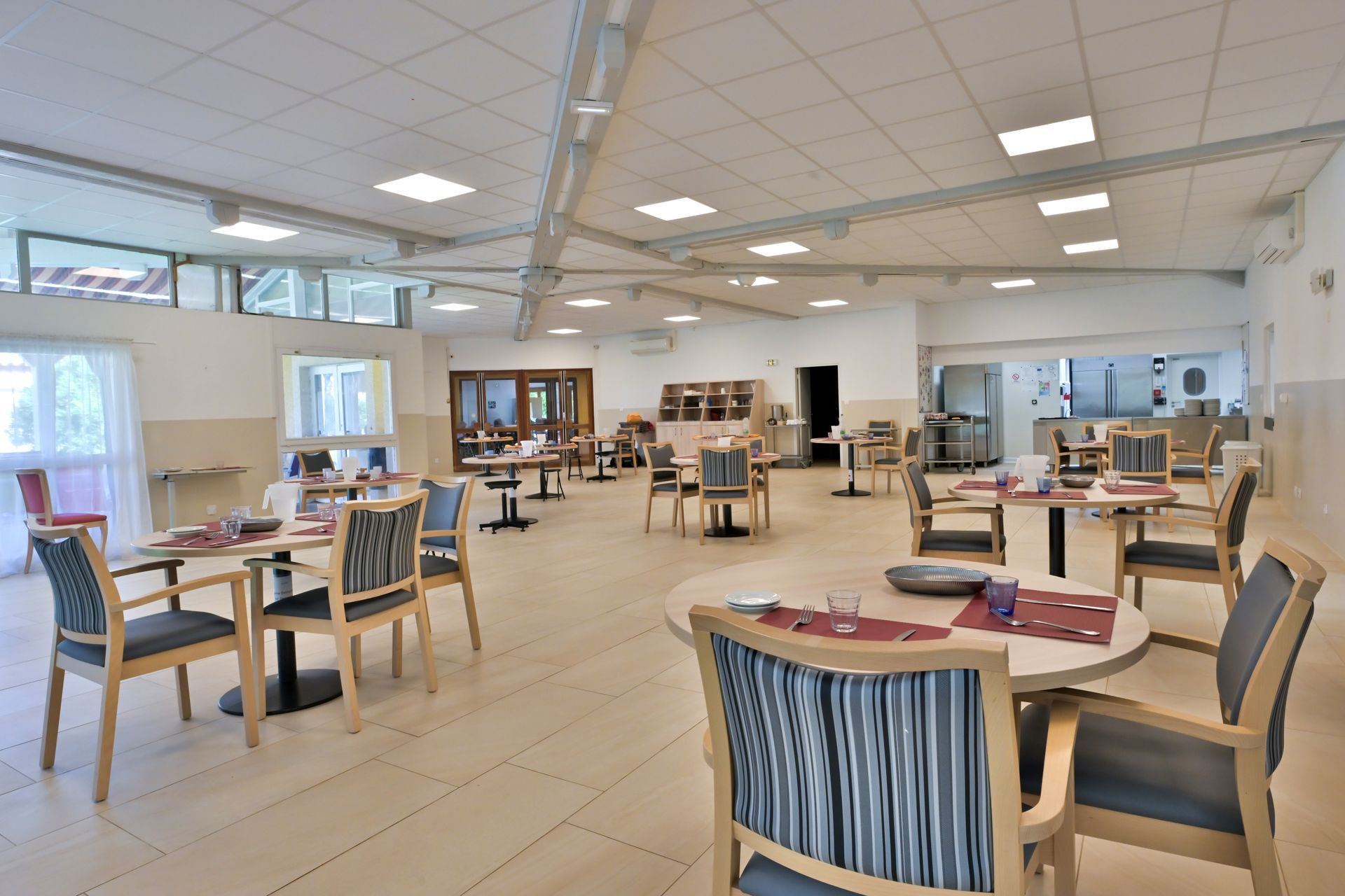 Une salle à manger avec des tables rondes et des chaises aux coussins à rayures bleues.