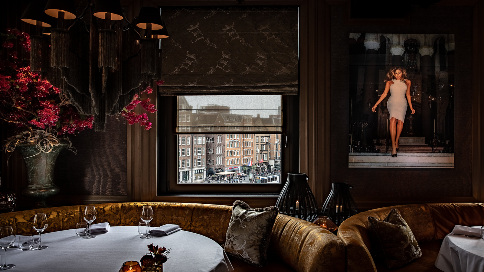 Luxe restaurantinterieur van restaurant Bougainville. Ronde, gouden bank met wit tafelkleed, raam en groot bloemstuk.