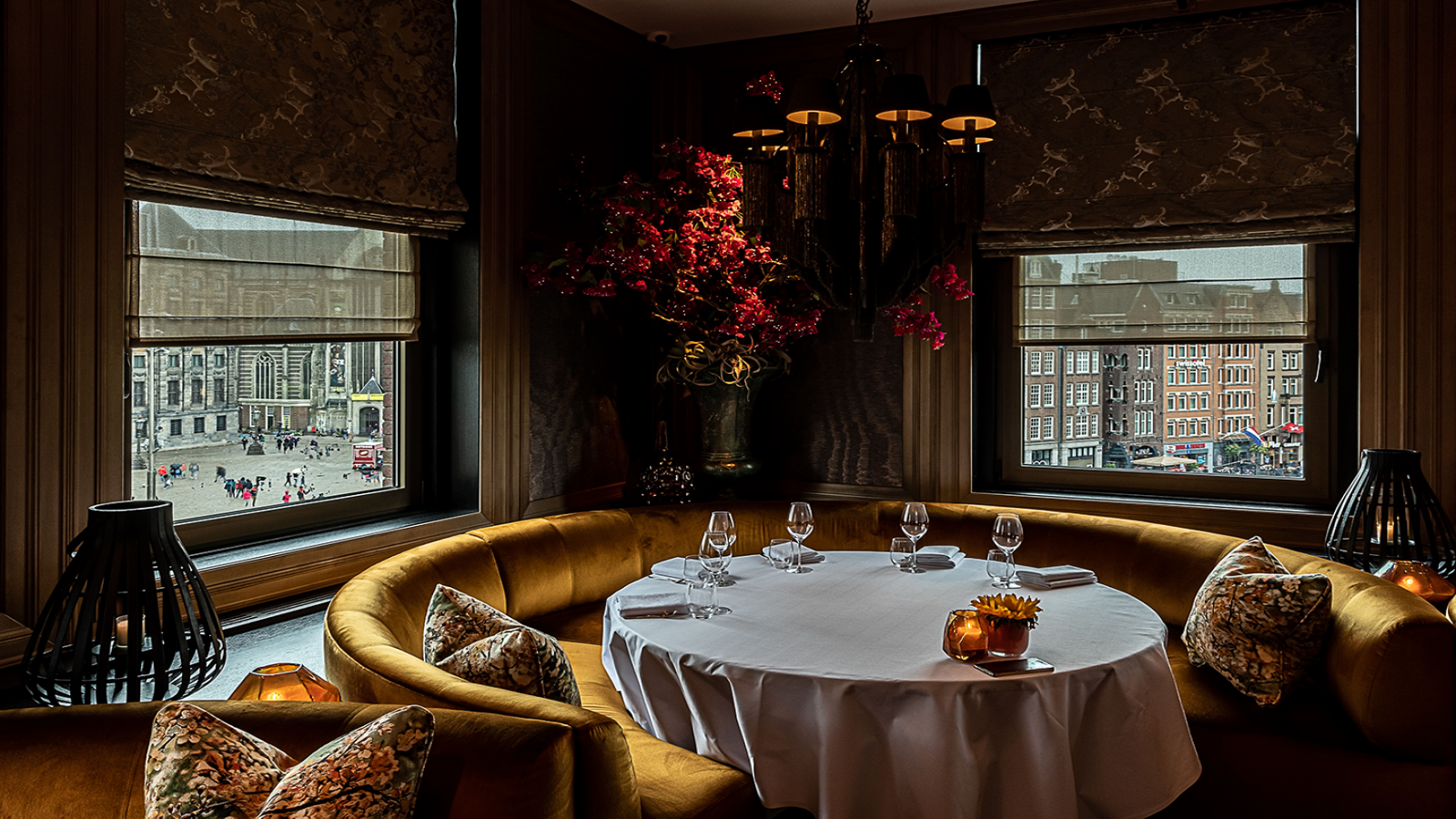 Een ronde, luxe eethoek restaurant Bougainville met een gedekte tafel, terwijl u via de ramen uitkijkt op het stadsgezicht.