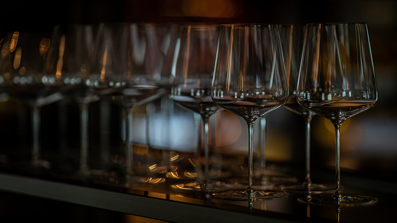 Wijnglazen stonden op een plank opgesteld en weerkaatsten warm licht.