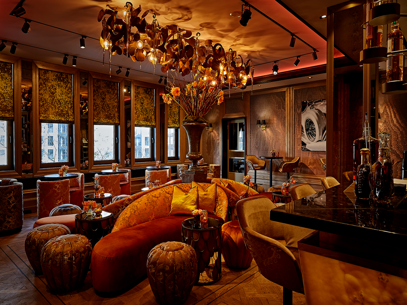 Luxe lounge Bar TwentySeven met oranje zitplaatsen, bloemenkroonluchter en bar.