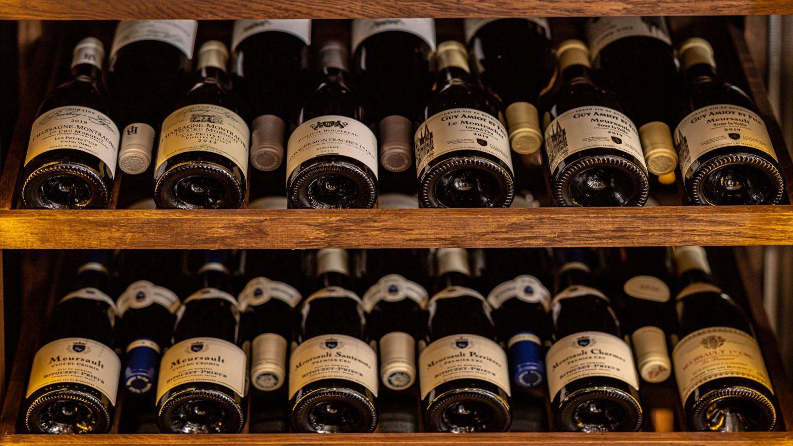Wijnflessen opgeslagen op houten planken in een kelder.