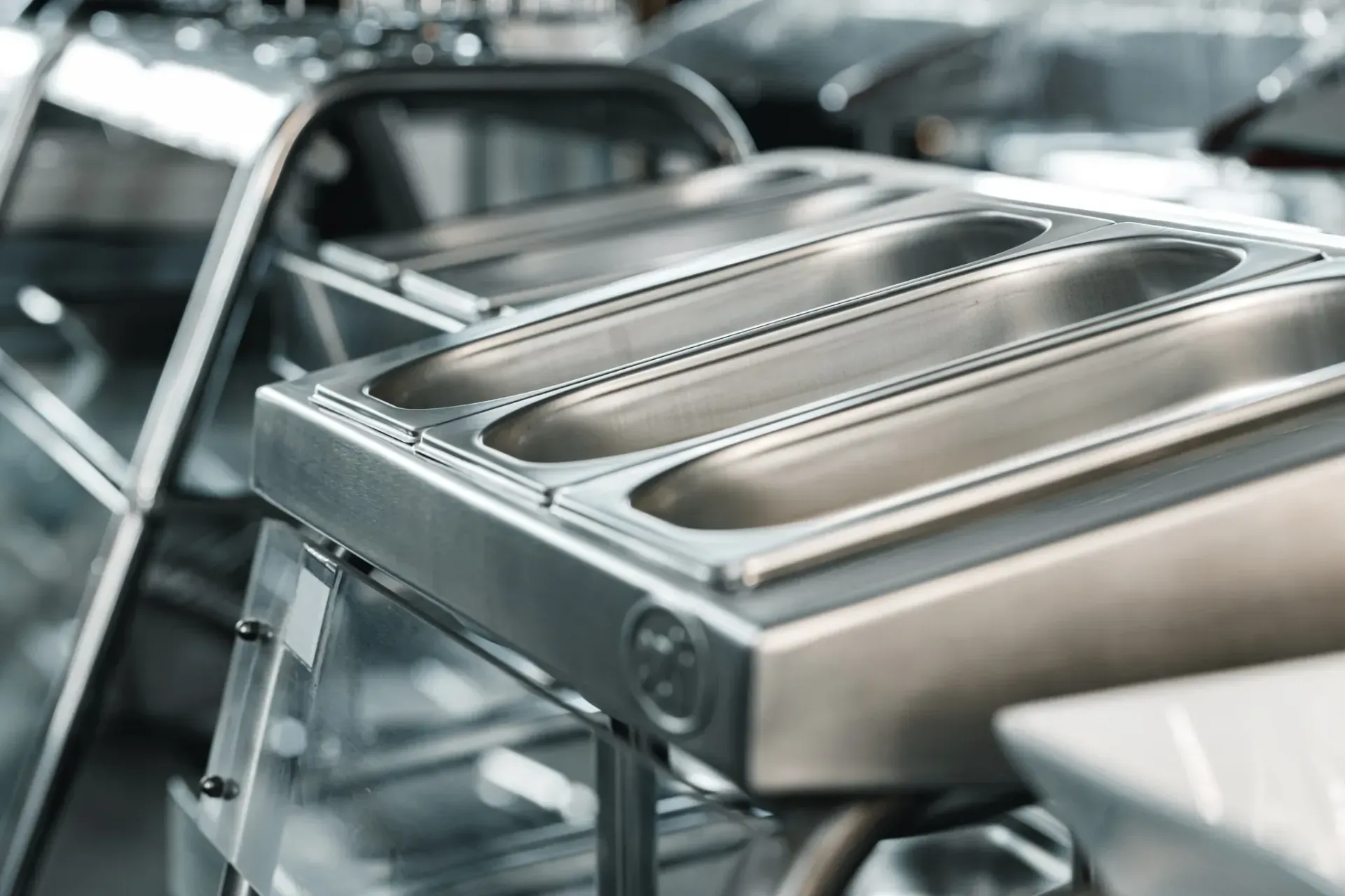 Bandejas de acero inoxidable para calentar alimentos apiladas en una cocina comercial.